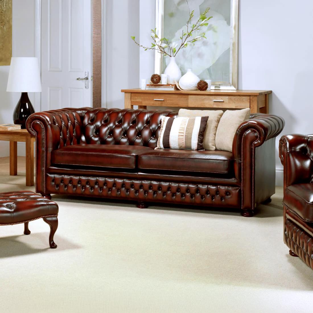 Stan Chesterfields Knight Sofa in klassischem Chesterfield-Design mit geradem Rücken, tiefgeknöpfter Rückenlehne, gedrechselten Holzfüßen und Antique Rub-off (Abwischleder) – stilvoll inszeniert in einem modernen Wohnraum - handgefertigt in England