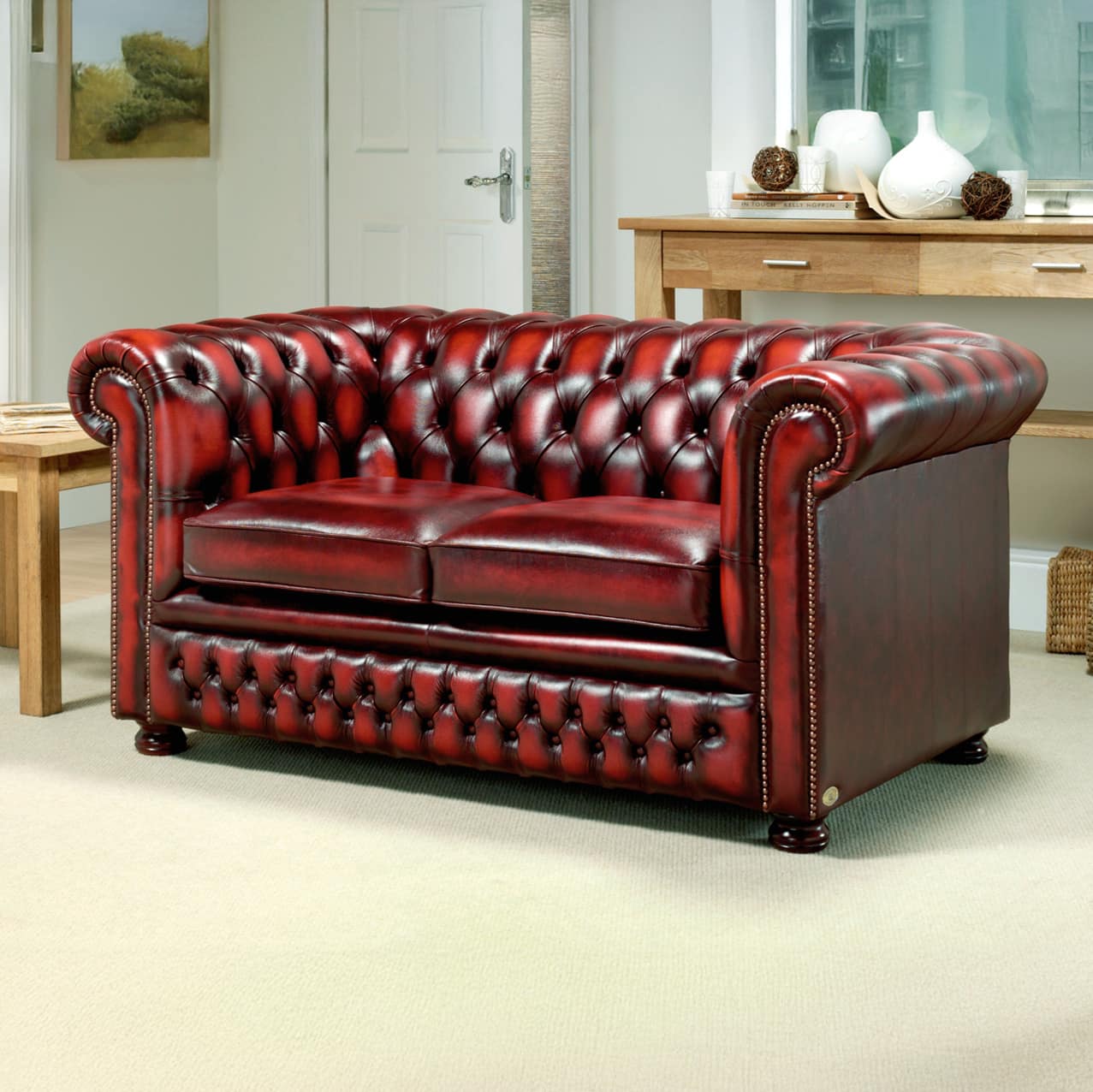 Stan Chesterfields Knight Sofa in klassischem Chesterfield-Design mit geradem Rücken, tiefgeknöpfter Rückenlehne, gedrechselten Holzfüßen und Antique Rub-off (Abwischleder) – stilvoll inszeniert in einem modernen Wohnraum - handgefertigt in England